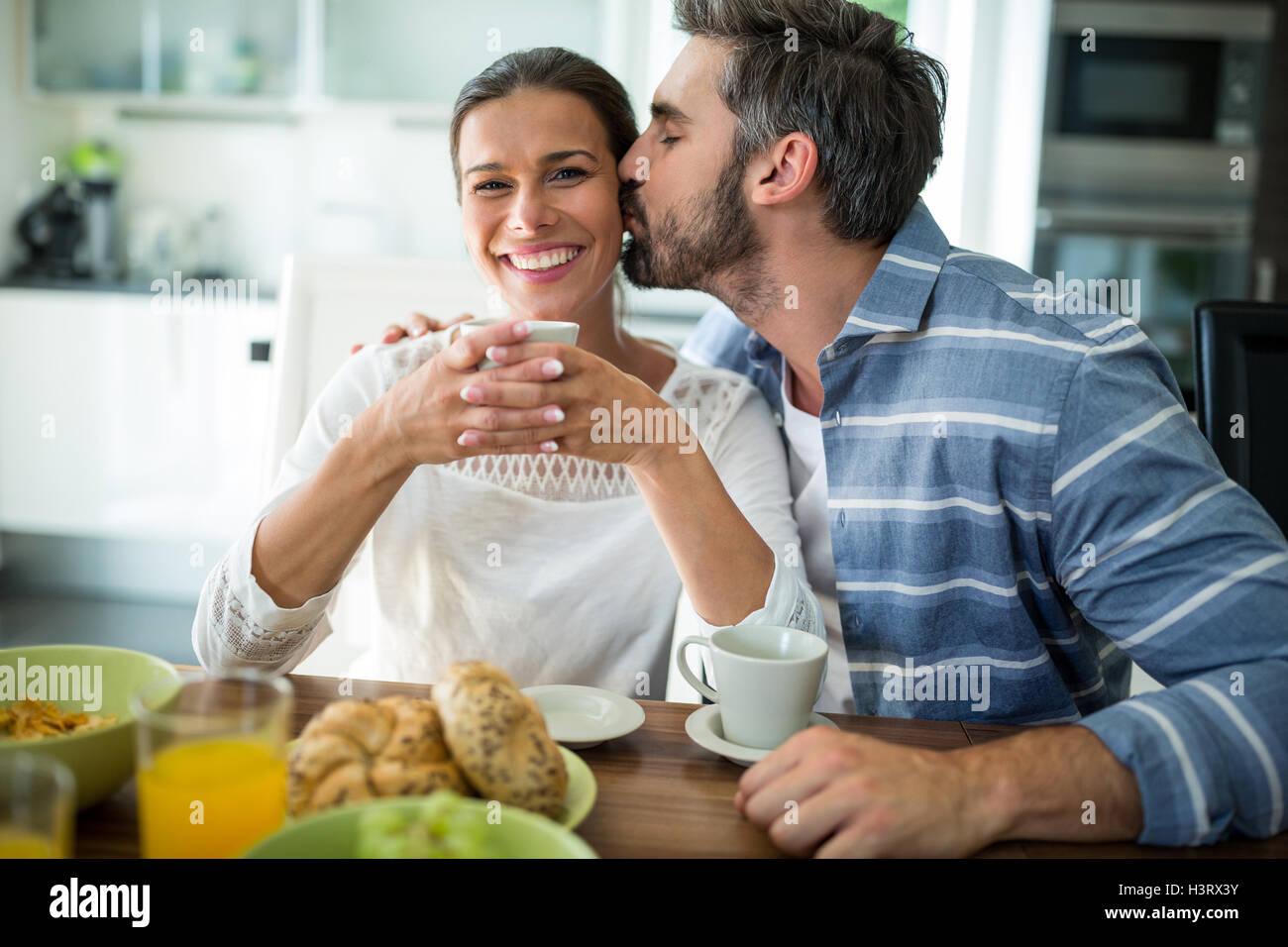 Mann beim Frühstück auf Frau Wangen küssen Stockfoto