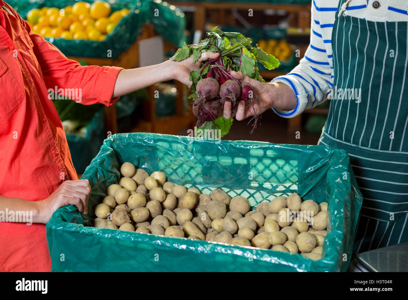Mitarbeiter, die Unterstützung der Frau bei der Auswahl der frische rote Beete Stockfoto