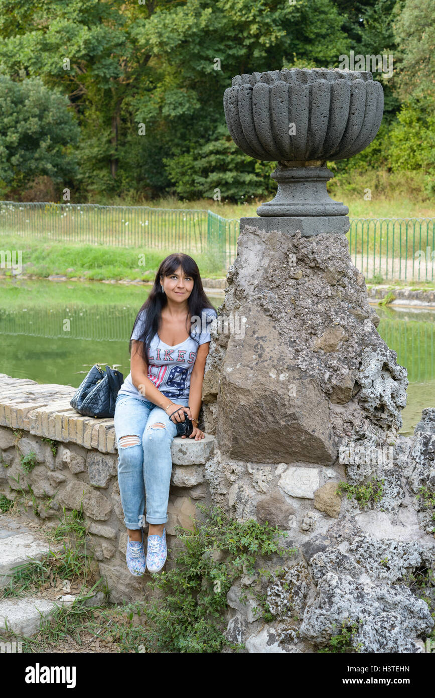 Mädchen posiert sitzen in der Nähe einer alten Ruine in einem Park von Rom, Italien Stockfoto