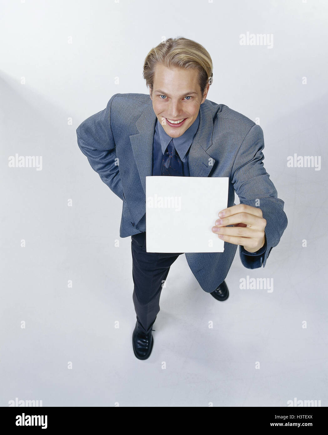 Mann, Lächeln, jung, Anzug, Blatt Papier, halten, präsent, Geste, Teenager, junger Mensch, stehen, halten Zettel Papier, Platzhalter, Point, Präsentation, Stimmung, fröhlich, glücklich, in einer guten Stimmung positiv, Studio, cut Outs, Stockfoto