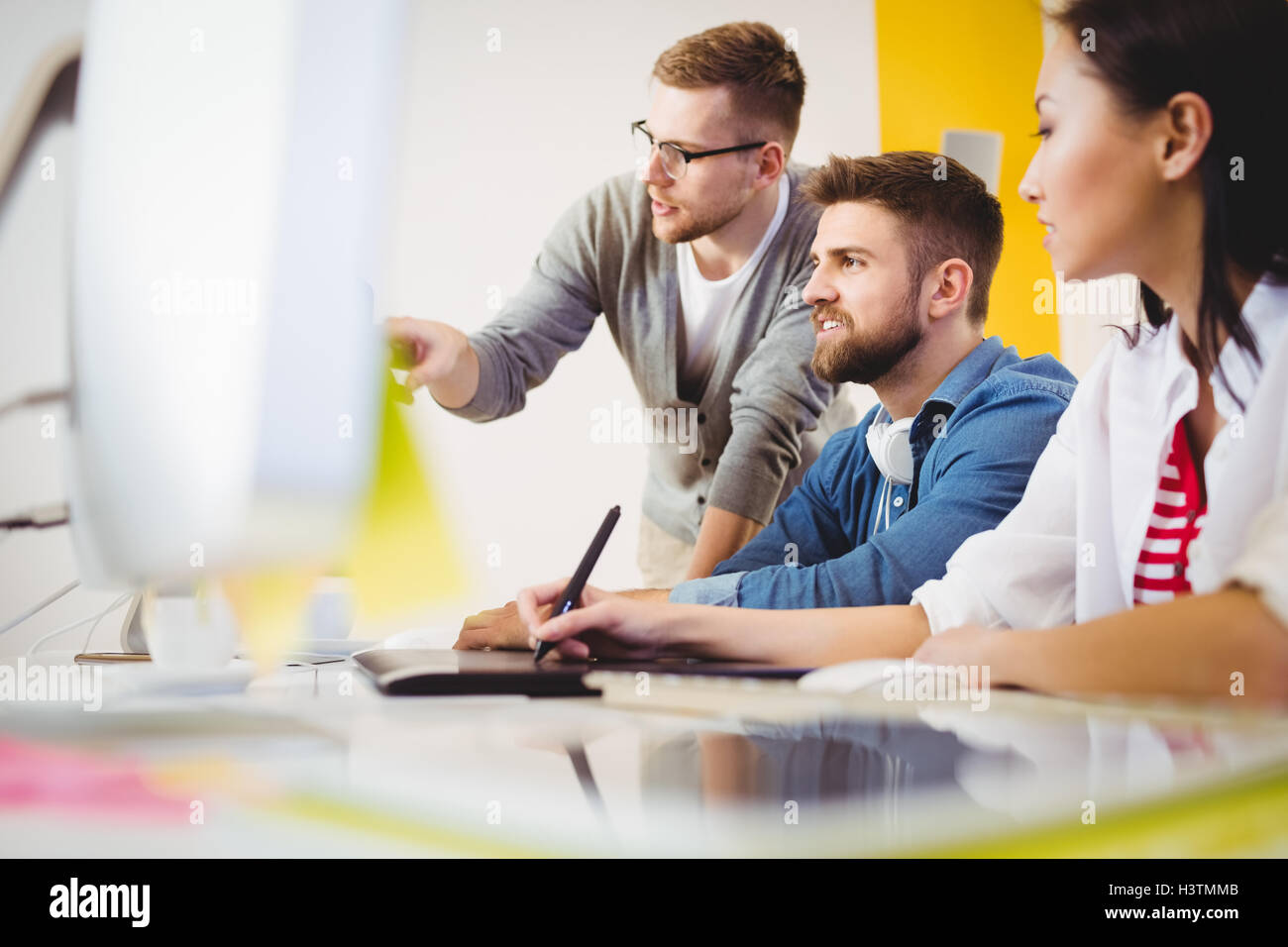 Exekutive auf Computer-Monitor zeigen Kolleginnen und Kollegen im Kreativbüro Stockfoto