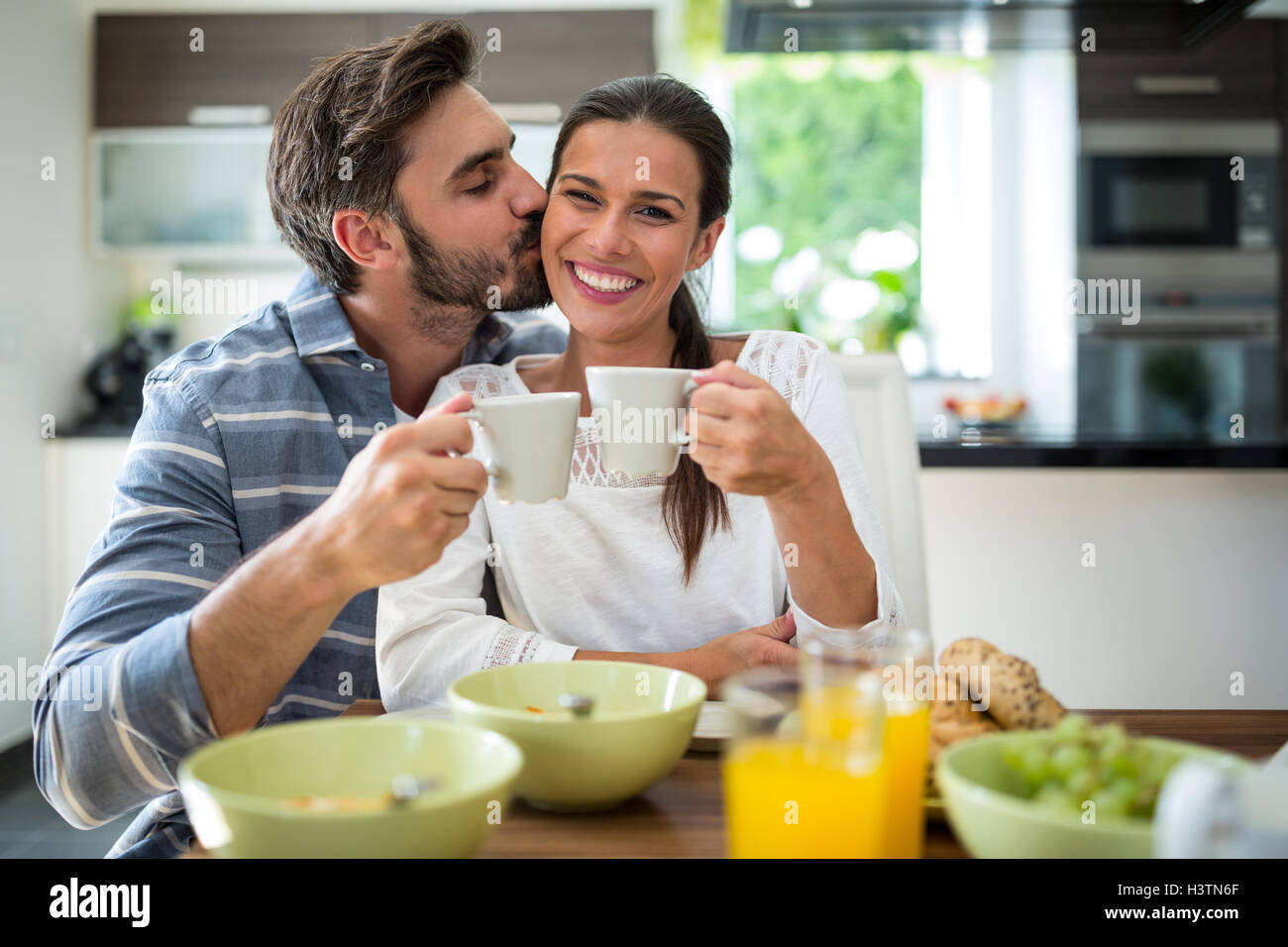 Mann beim Frühstück auf Frau Wangen küssen Stockfoto