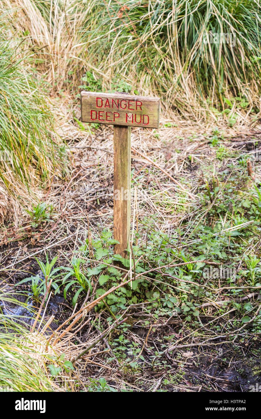 Rechteckiger Holzschild mit roten schreiben in sumpfigen Boden, Gefahr tiefen Schlamm Stockfoto