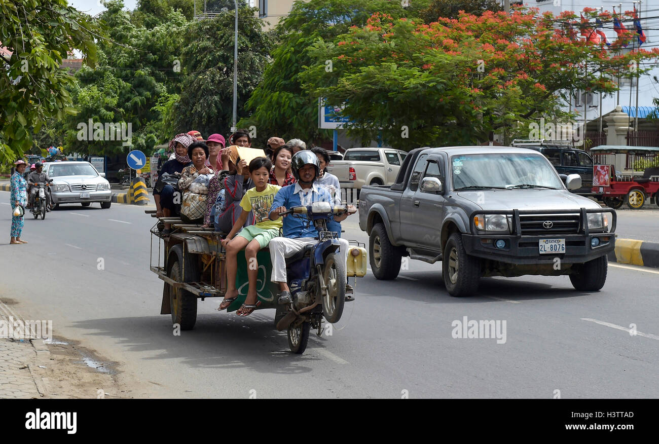 Mann auf Roller macht einen Wheelie, Anhänger beladen mit vielen Menschen, Phnom Penh, Kambodscha Stockfoto