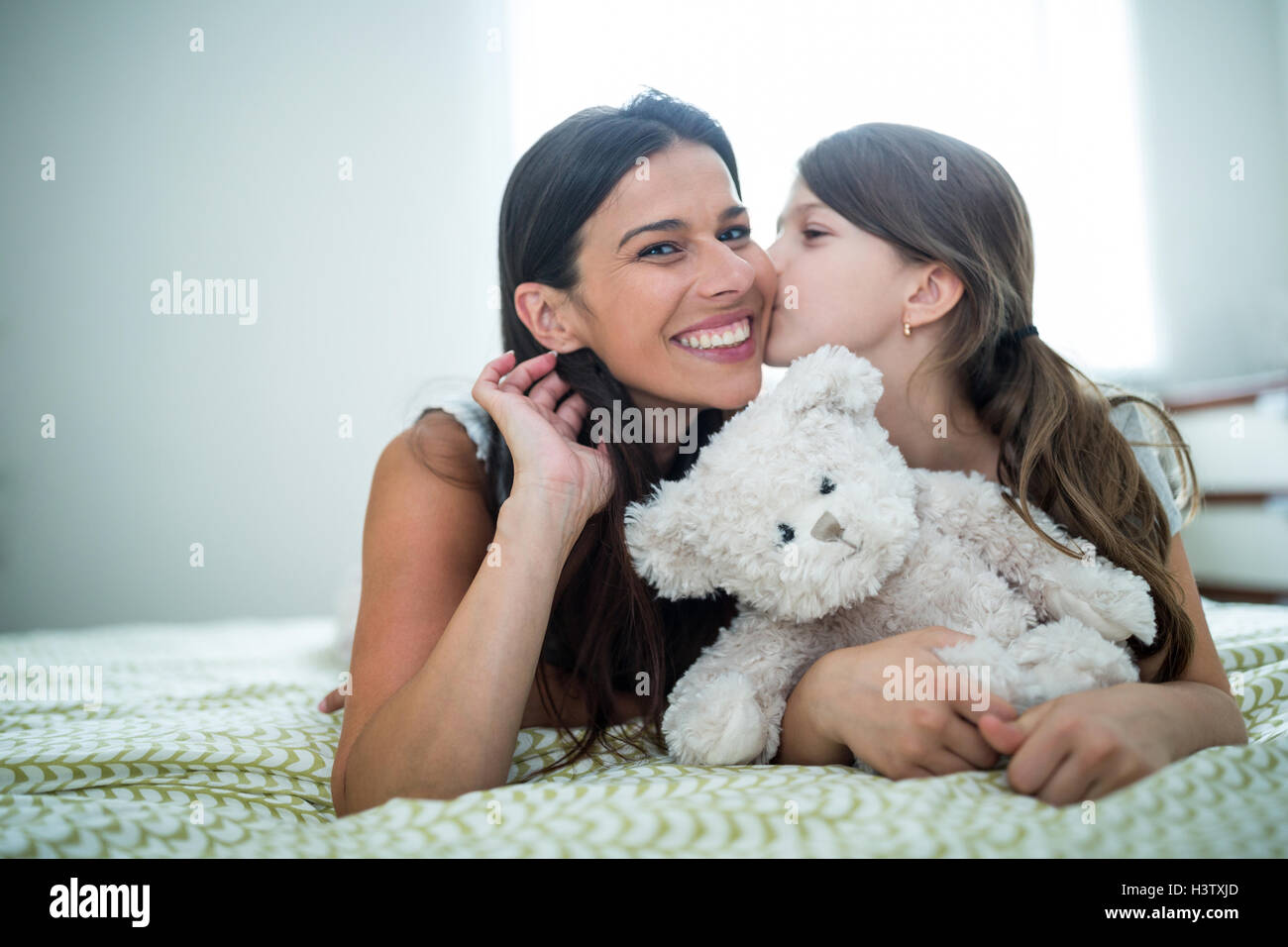 Tochter küssen auf Mutter Wangen auf Bett zu Hause Stockfoto