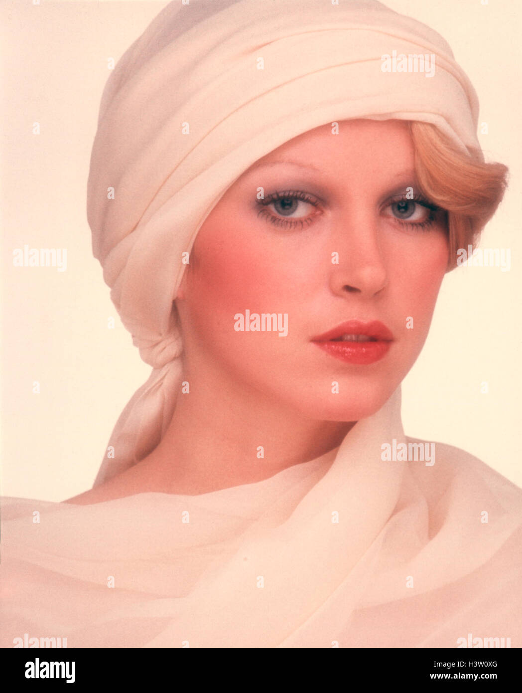 1970ER JAHRE PORTRAIT HÜBSCHE BLONDE FRAU WEIßEN TURBAN STIL HUT BLICK IN DIE KAMERA Stockfoto