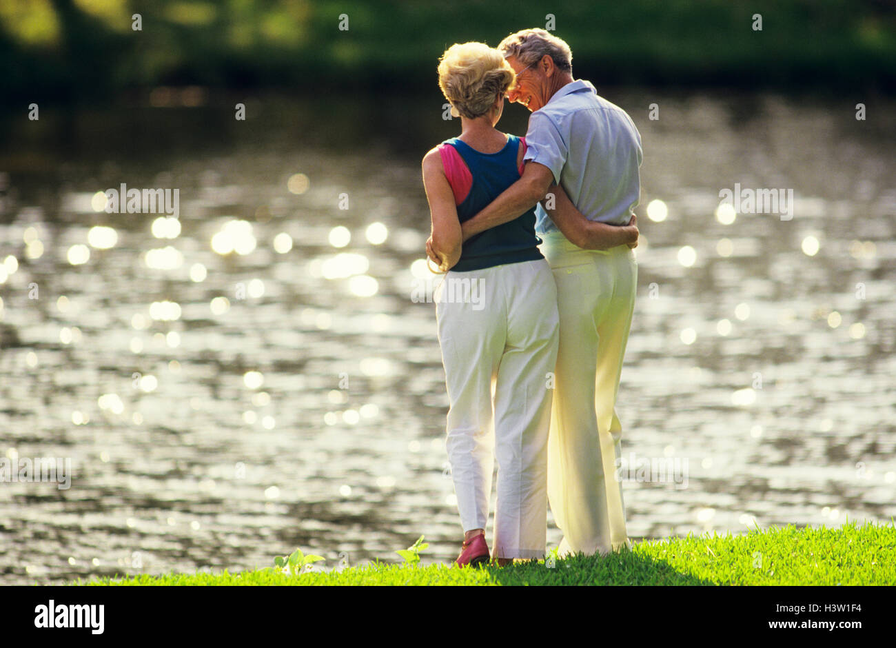 RÜCKANSICHT DES ROMANTISCHEN ÄLTERES PAAR AM SEE 'S EDGE Stockfoto