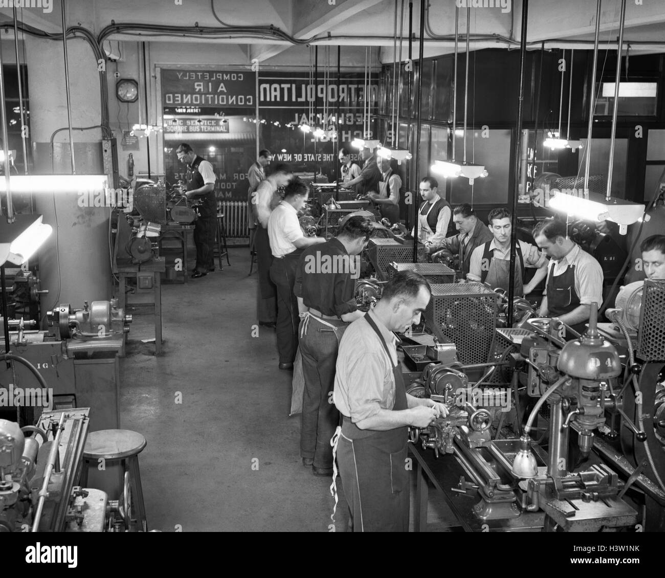 1940S 1950S MÄNNER TRAGEN MASCHINIST SCHÜRZEN ARBEITEN DREHMASCHINEN INDOOR BEI METROPOLITAN INDUSTRIESCHULE Stockfoto