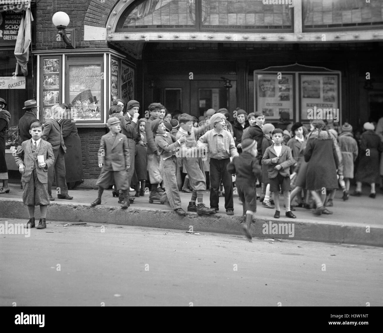 1920S 1930S NACHBARSCHAFT JUNGEN UND MÄDCHEN WARTEN KOMMT MAN IN EINE FILM-MATINEE IN WATERBURY, CONNECTICUT USA Stockfoto