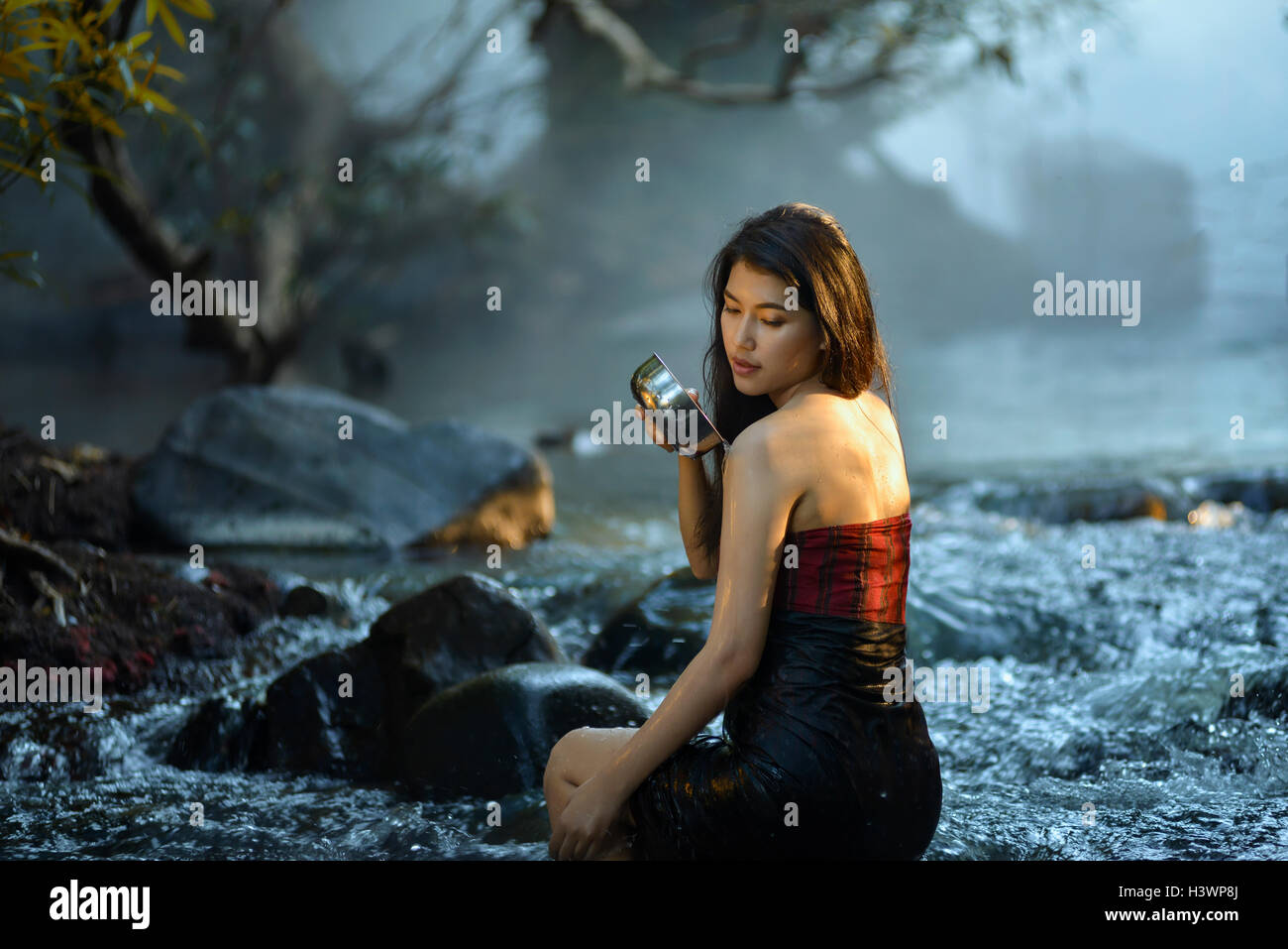 Frau sitzt in einem Fluss Baden, Thailand Stockfoto