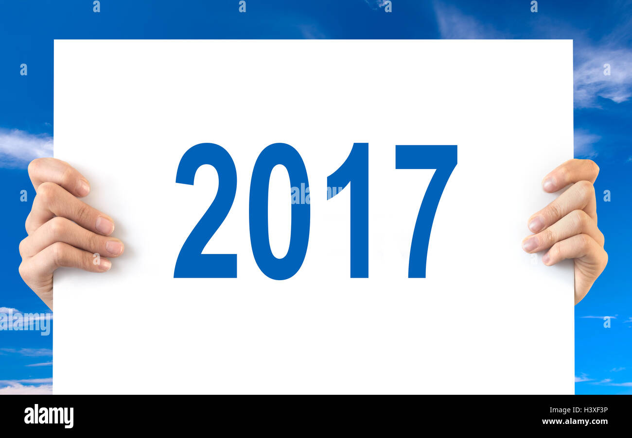 Hände halten eine weiße Tafel mit 2017, blauen Himmelshintergrund Stockfoto