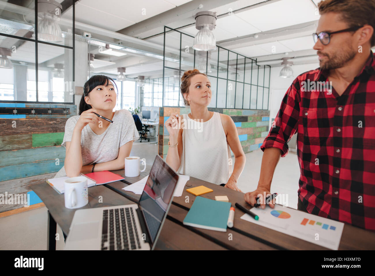 Gruppe von Jugendlichen diskutieren neue Geschäftsideen in einer Besprechung. Start-Sitzung an einem Tisch im modernen Büro. Stockfoto