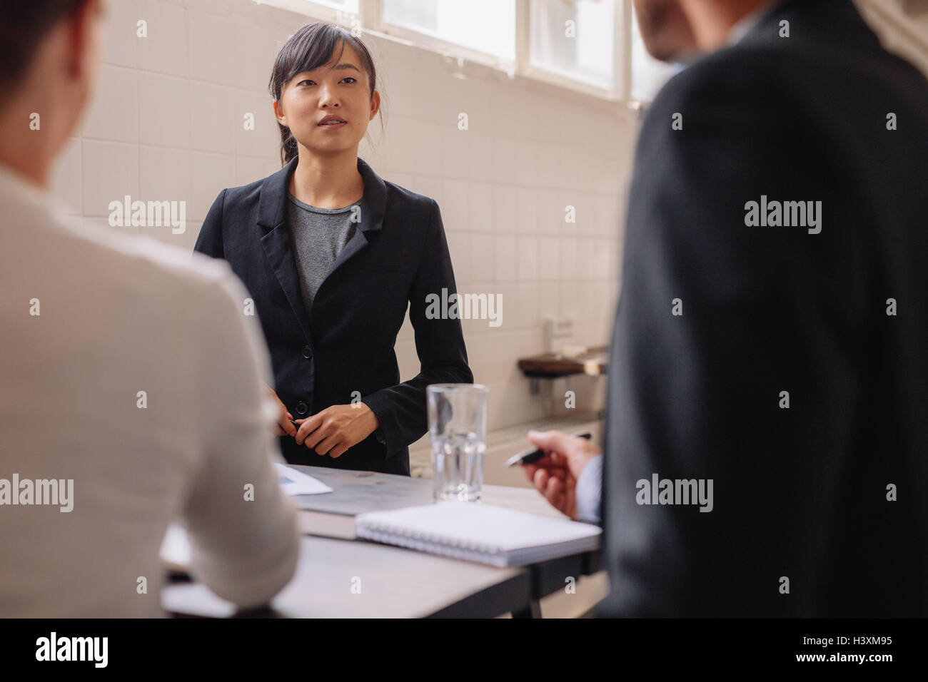 Junge asiatische Geschäftsfrau, die Interaktion mit Kollegen während Business-Präsentation. Unternehmer treffen an einem Tisch. Stockfoto