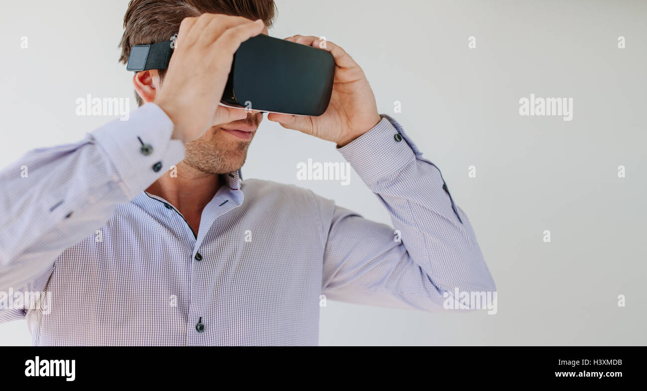 Schuss der junge Mann mit virtual-Reality-Brille vor grauem Hintergrund hautnah. Kaukasischen Männchen mit VR-Brille. Stockfoto