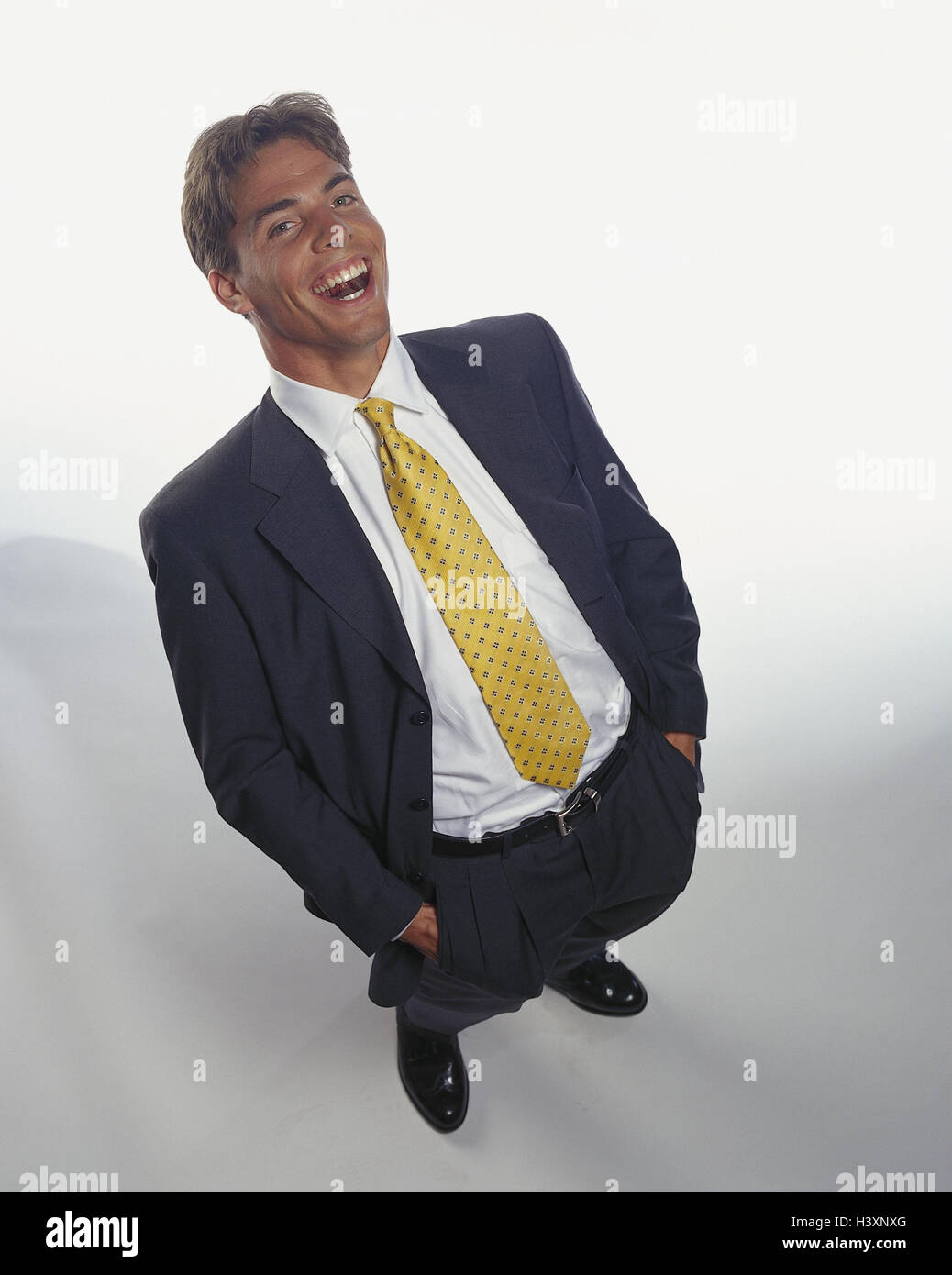 Geschäftsmann, lachen, Hände, Hosentaschen, Mann, Anzug, jung, Ständer, Geste, in Studio, Freisteller, von oben Stockfoto