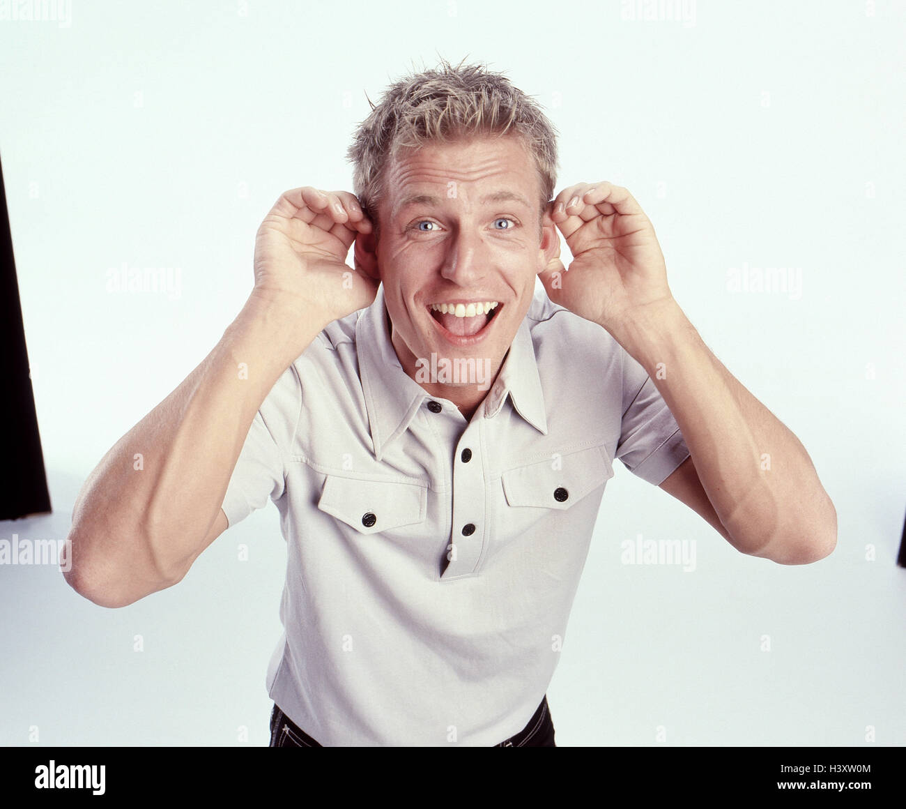 Mann, jung, Geste, hören, glücklich, Männer, Studio, Freisteller, Blond, Körpersprache, zuhören, Neugier, Achtung, neugierig, zuhören, lachen, halbe Portrait Stockfoto