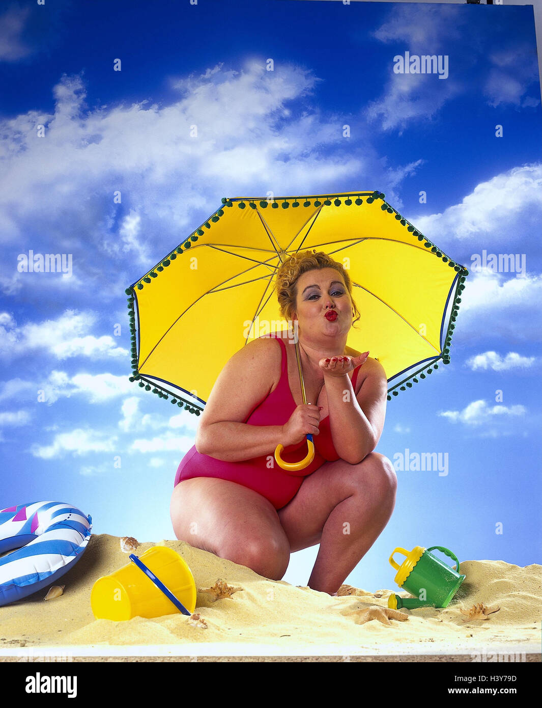 dicke Frau, Badeanzug, gelbe Sonnenschirm am Strand, bewölkter Himmel,  Studio mb 69 A7 Ausschneiden Stockfotografie - Alamy
