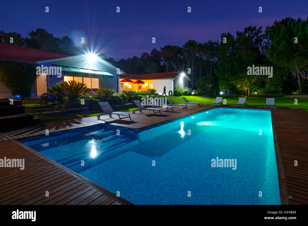 Nachtfoto eines großen Hauses mit beleuchtetem Außenpool Stockfoto