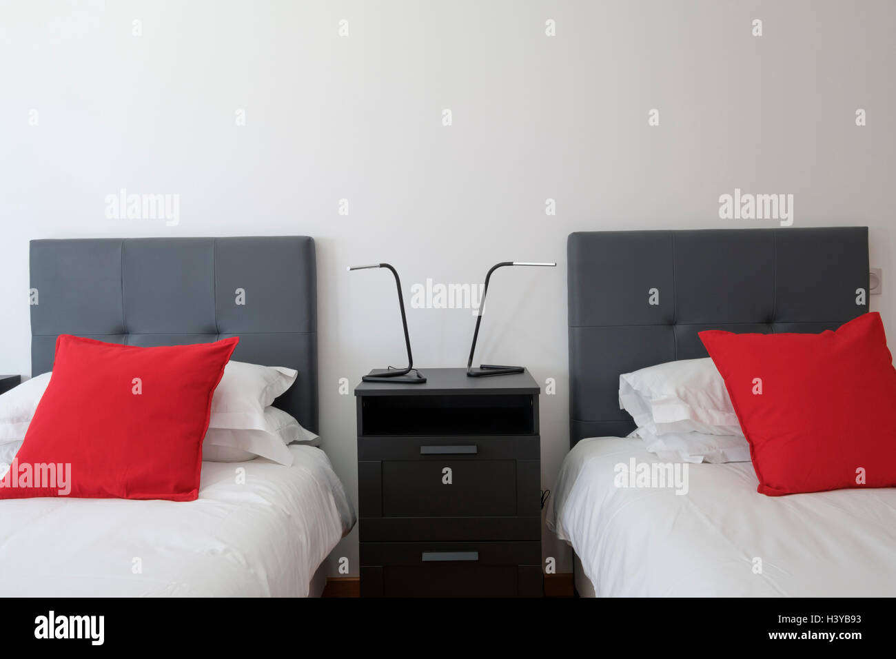 Zwei Einzelbetten nebeneinander mit einem Nachttisch aus dunklem Holz Stockfoto