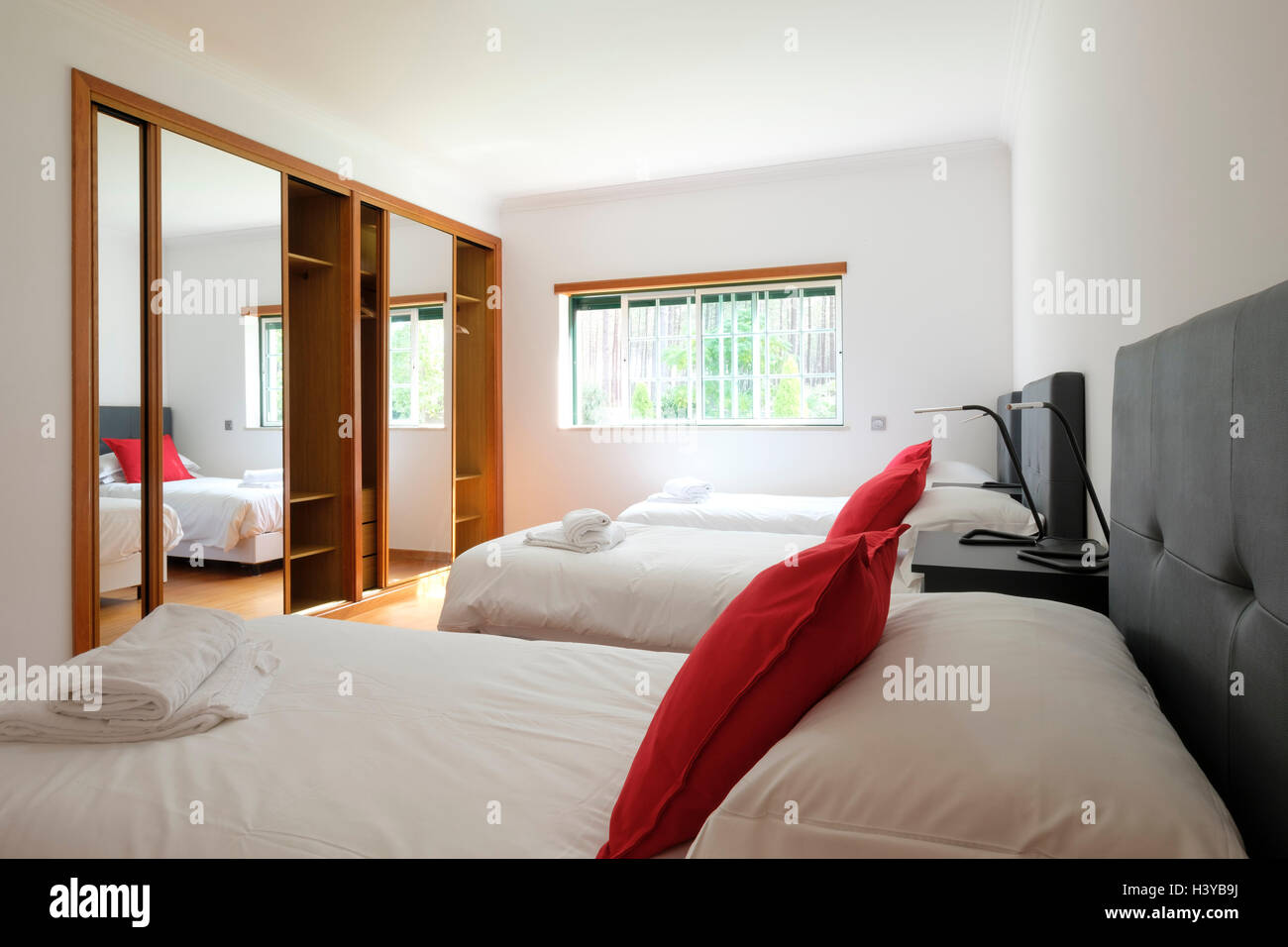 Sonnenbeleuchtetes Schlafzimmer mit drei Betten nebeneinander Stockfoto