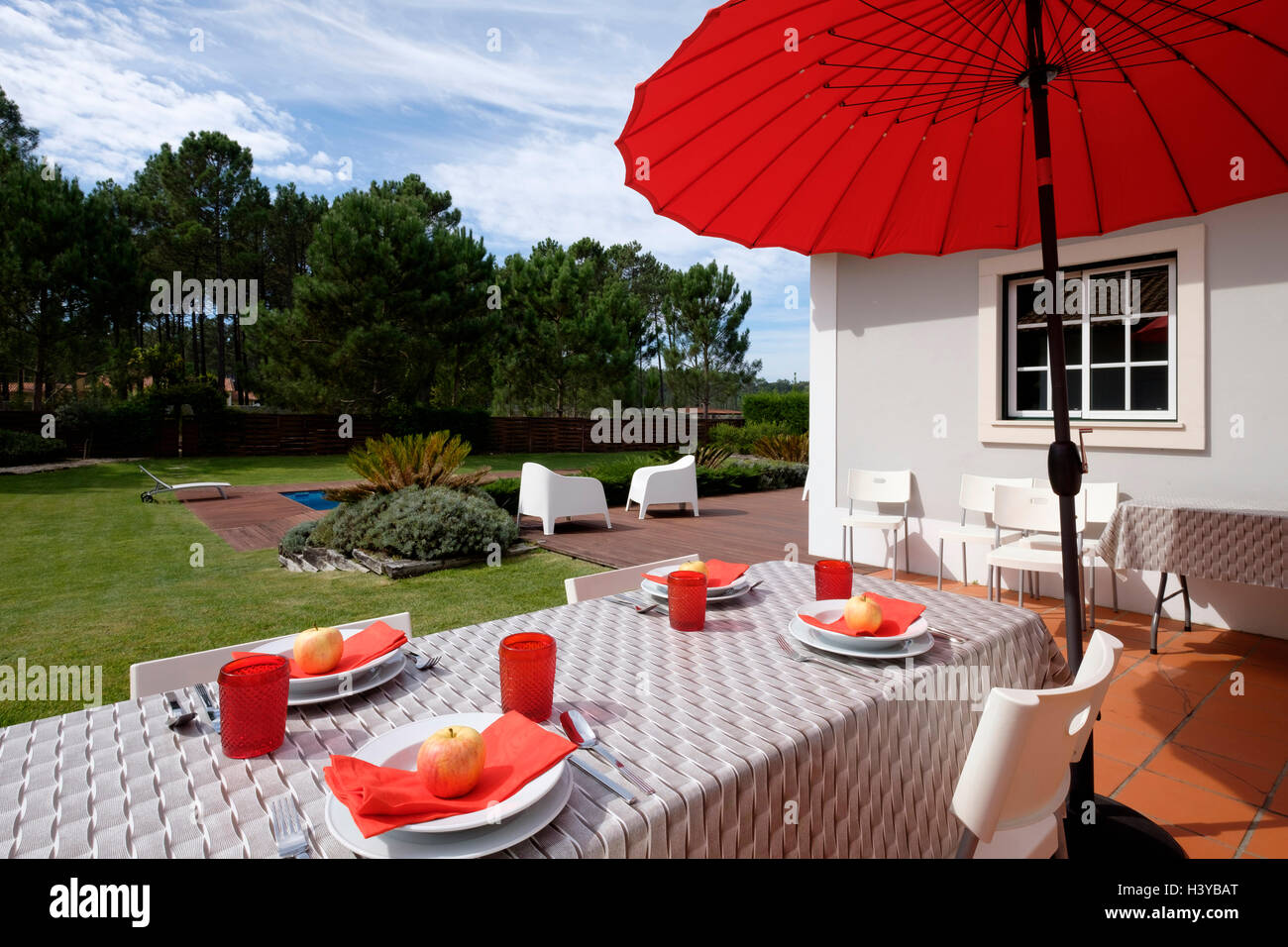 Sonnige Gartenszene im Innenhof mit Tisch für vier Personen Stockfoto