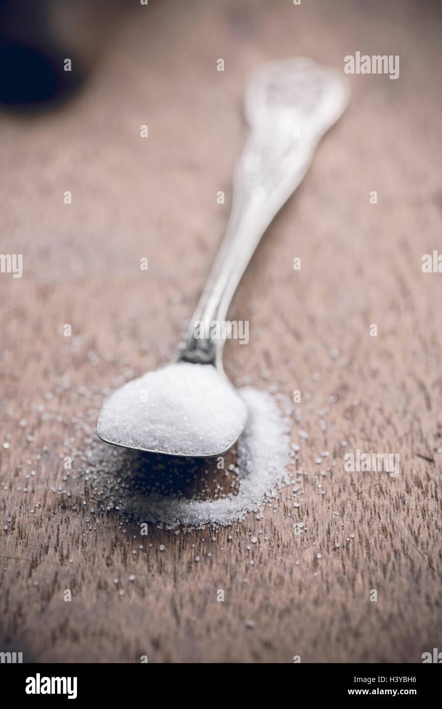 Salz auf einem Löffel in der Nähe auf. Holztisch als Hintergrund mit Textfreiraum. Stockfoto