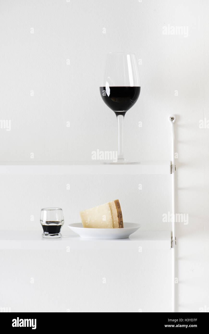 Rotwein, Parmesan und Balsamico-Essig im Bücherregal. Essen-Stilleben. Stockfoto