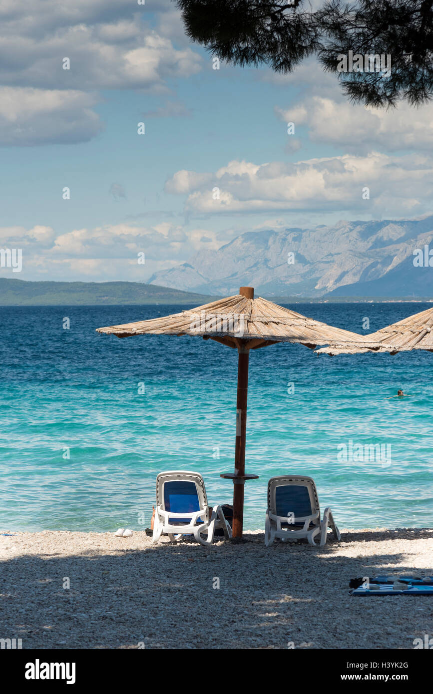 Ein Stroh Sonnenschirm oder Ampelschirm und Sonne liegen am Strand von Trpanj Kroatien im Sommer mit einem blauen Meer und Himmel im Sommer Stockfoto