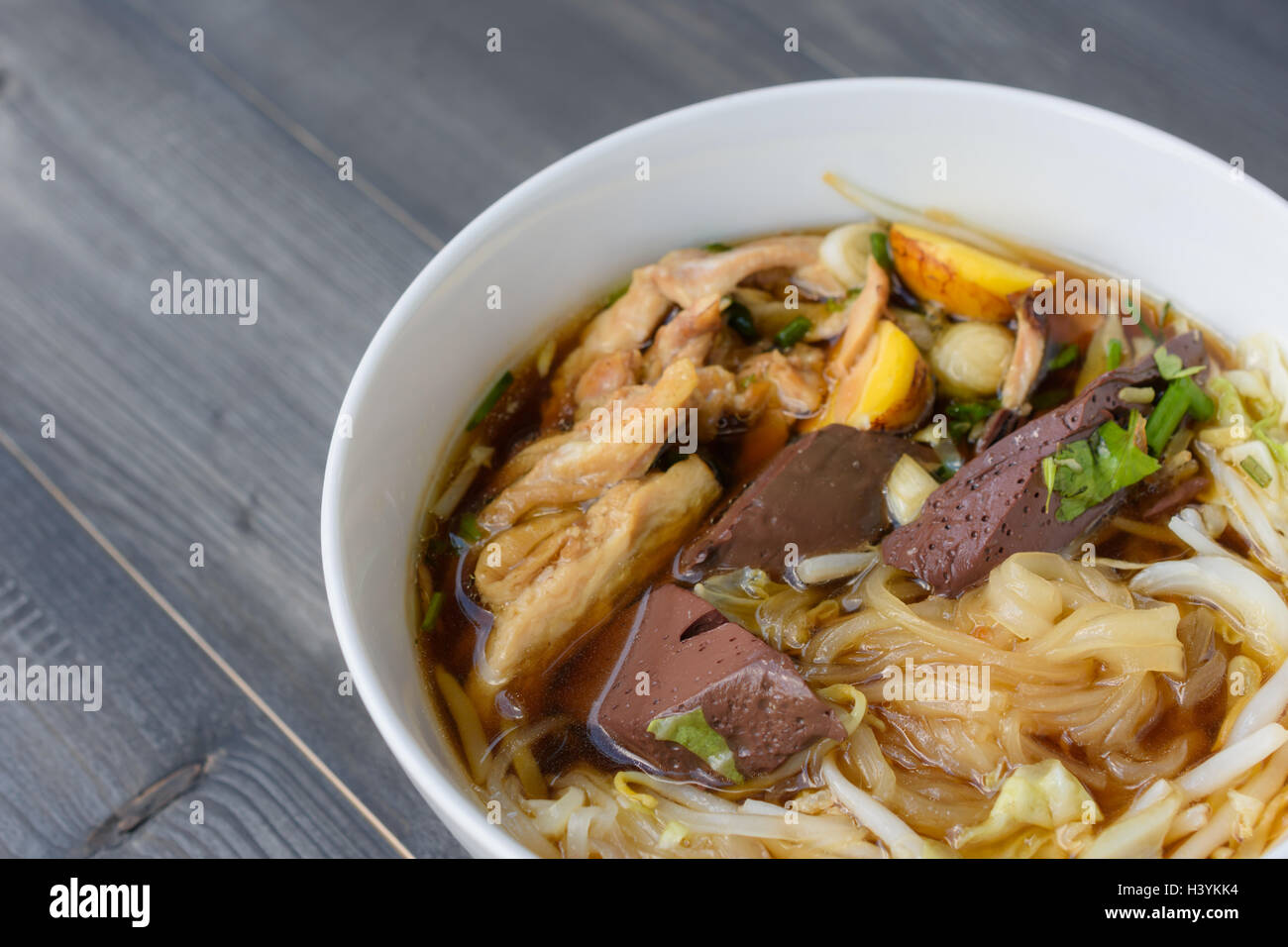 Nudelsuppe in Schüssel auf einem Holztisch, thailändische Spezialitäten Stockfoto