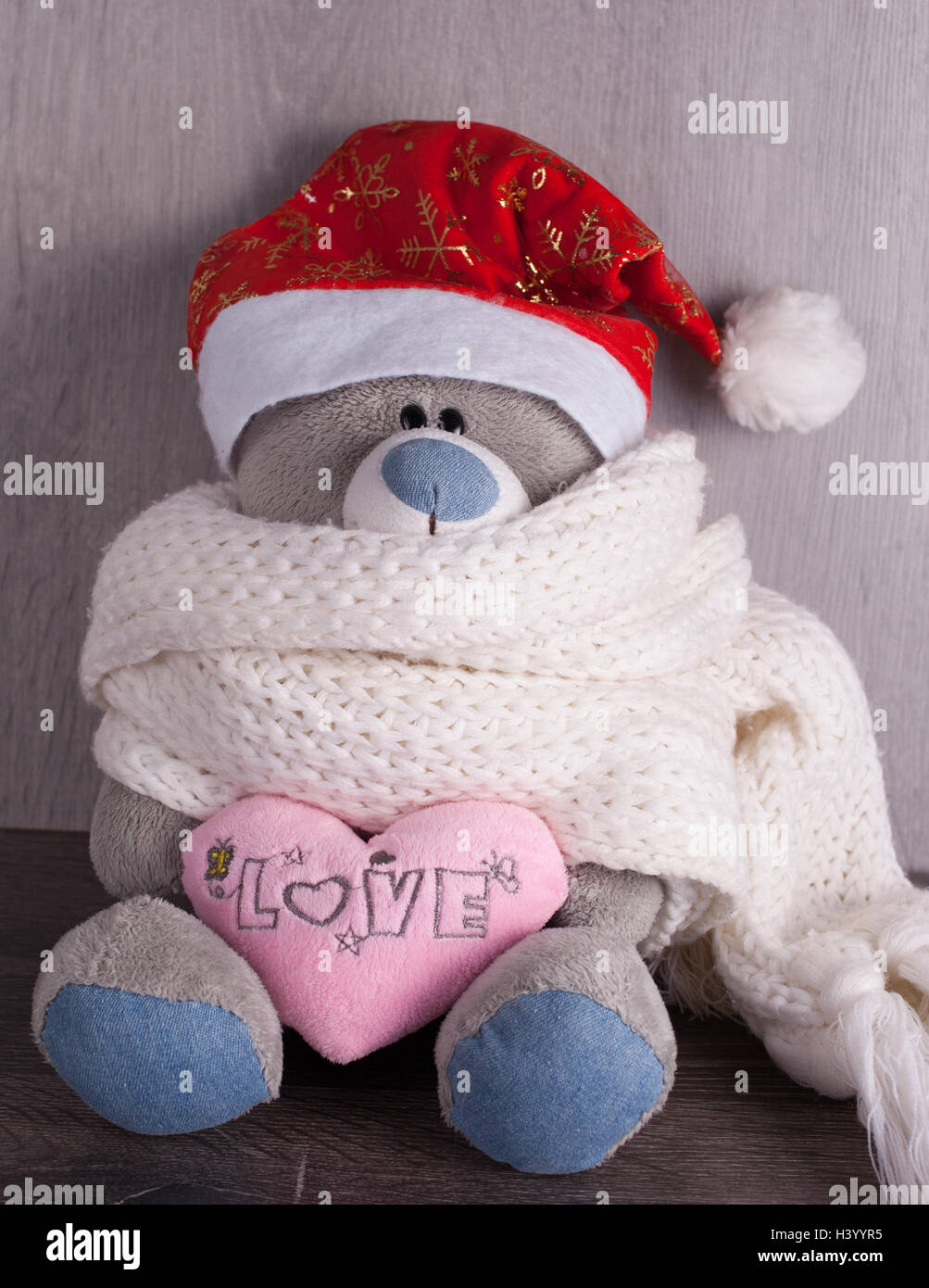 Weihnachtsspielzeug Bär mit Weihnachtsmütze auf hölzernen Hintergrund. Die Inschrift auf dem Herzen, ich liebe dich Stockfoto
