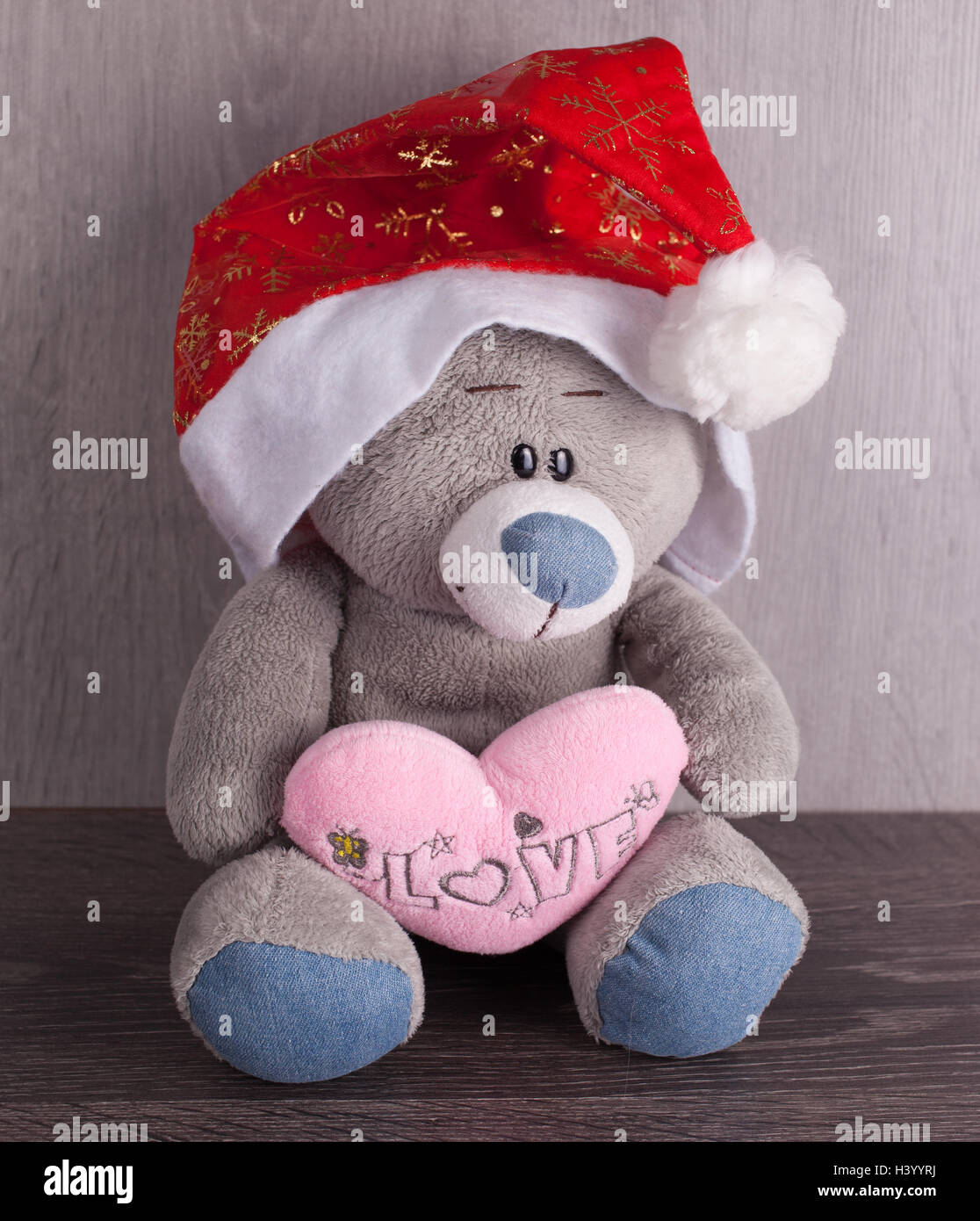 Weihnachtsspielzeug Bär mit Weihnachtsmütze auf hölzernen Hintergrund. Die Inschrift auf dem Herzen, ich liebe dich Stockfoto