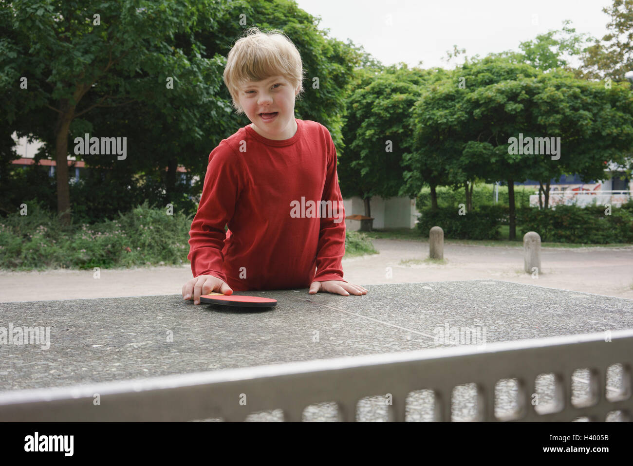 Porträt von glücklichen behinderten Jungen am Tischtennis-Tisch im Park stehen Stockfoto