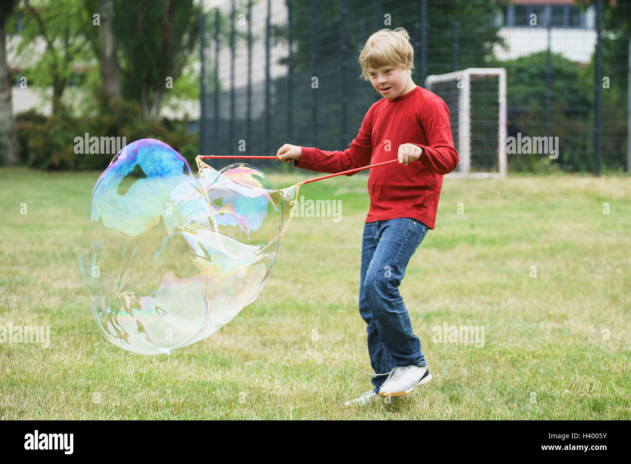 Behinderte junge spielt mit Seifenblasen im park Stockfoto