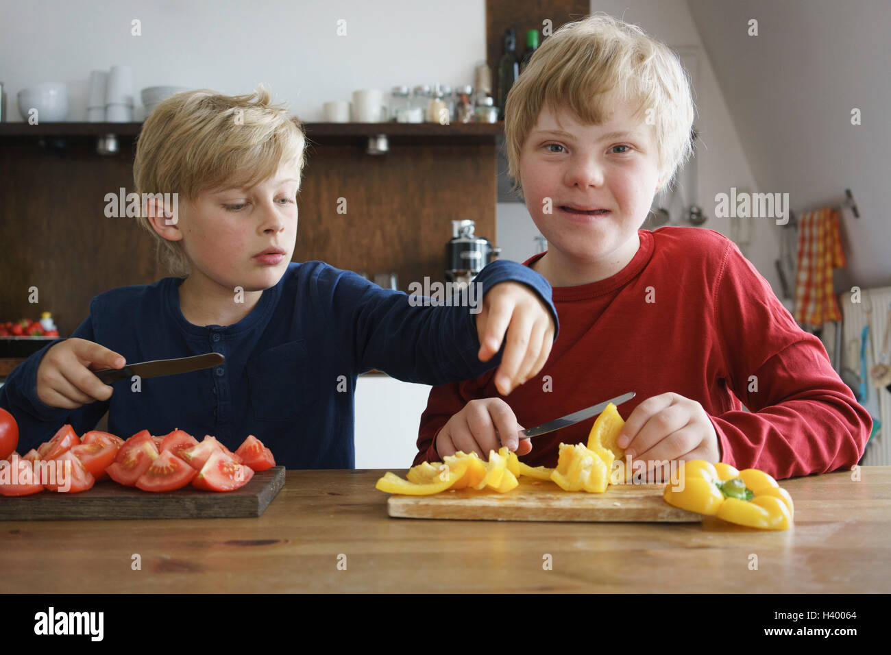 Porträt von behinderten Jungen sitzen mit Bruder am Tisch mit Gemüse in der Küche Stockfoto
