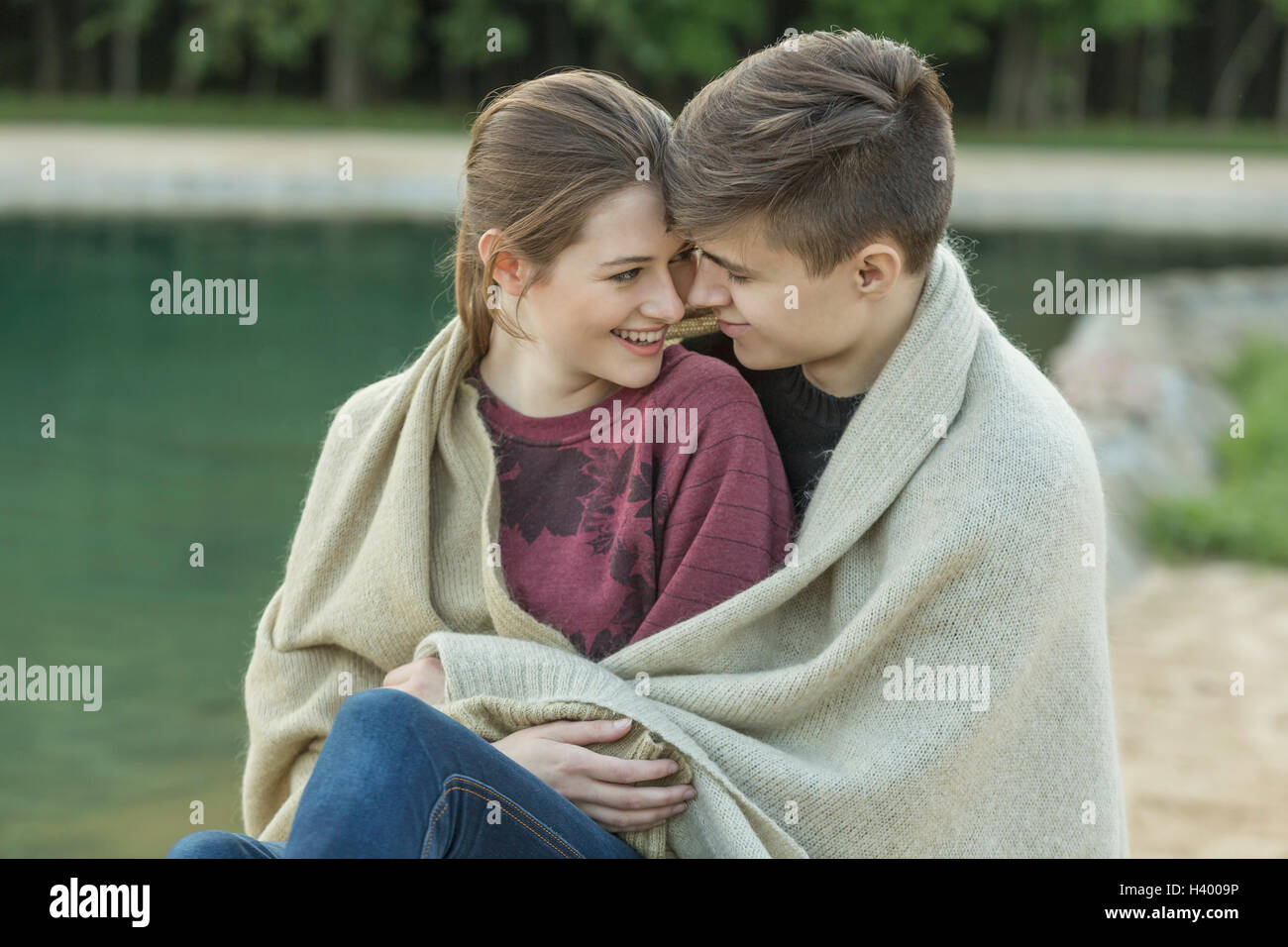 Lächelnde junge Liebespaar in ruhenden See Decke gehüllt Stockfoto