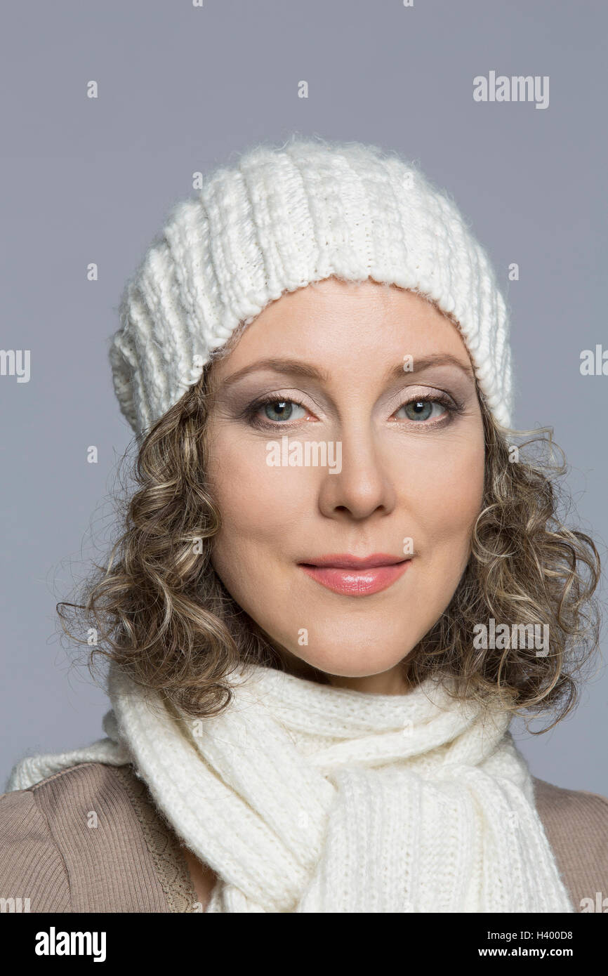 Portrait der schönen Frau mit lockigem Haar tragen stricken Hut vor grauem Hintergrund Stockfoto
