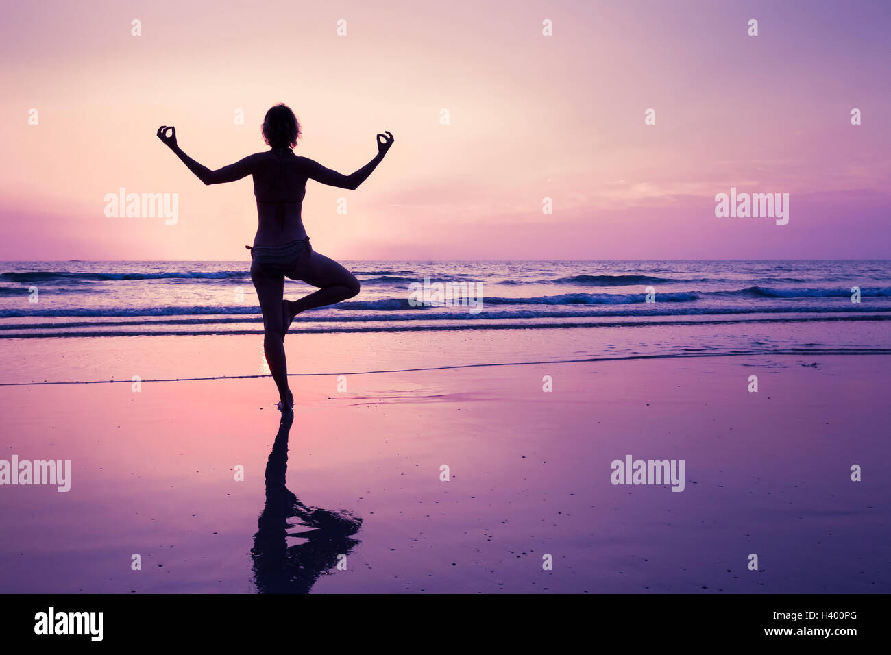 Junge Frau Entspannung mit Yoga am Strand bei Sonnenuntergang Stockfoto