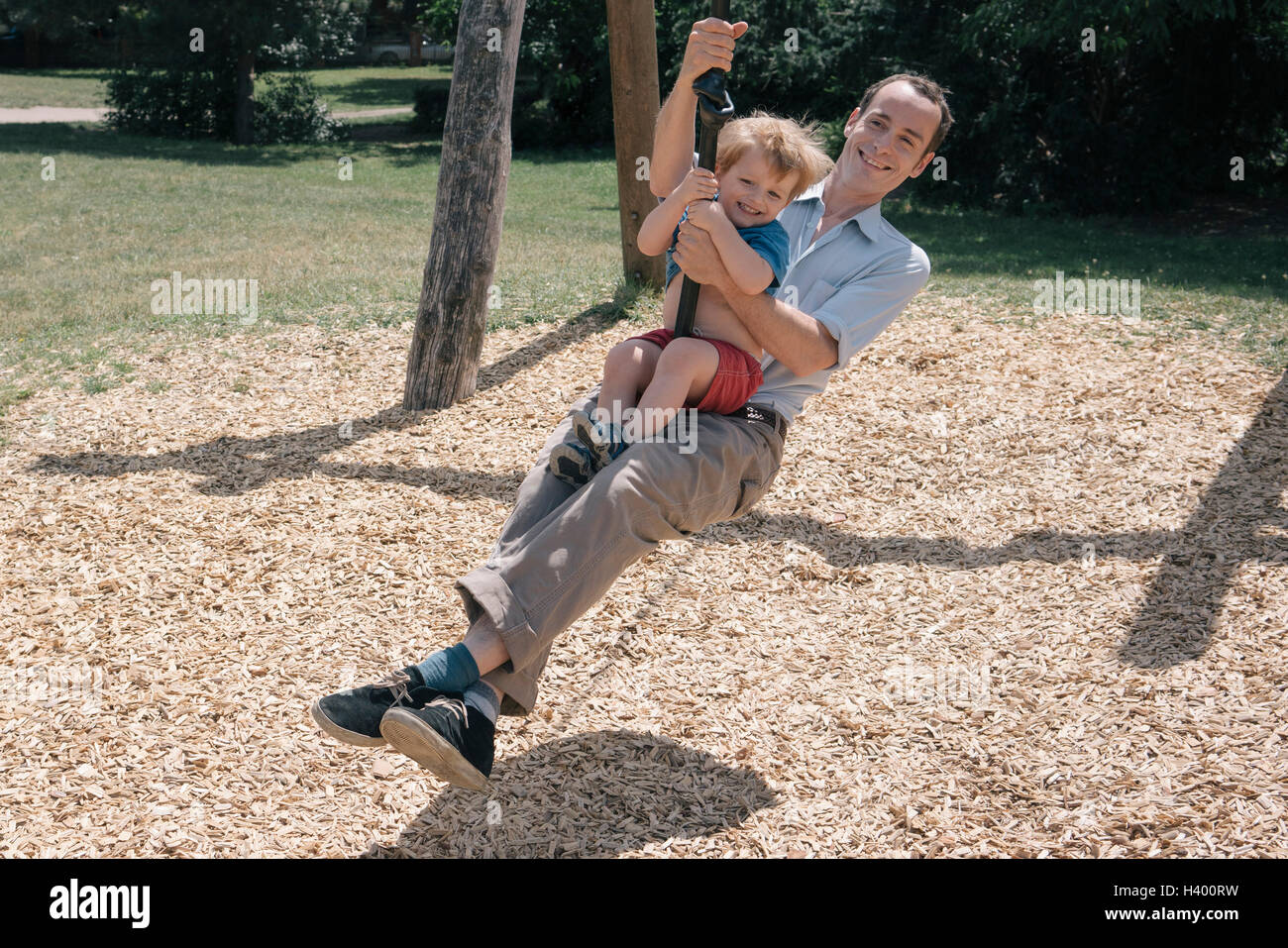 Fröhliche Vater mit Sohn auf Spielplatz Schaukeln Stockfoto