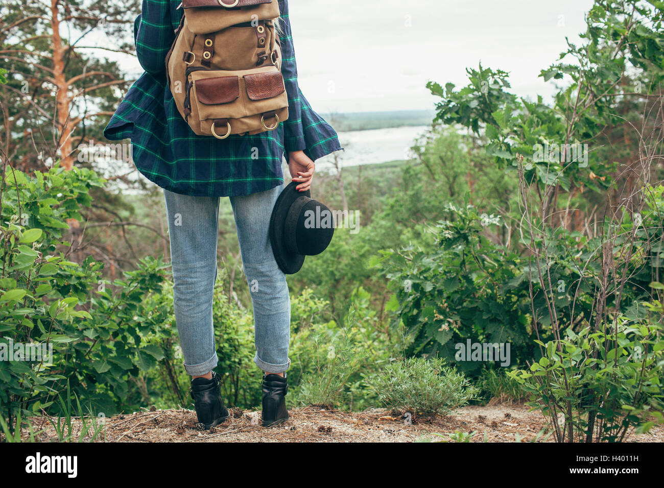 Niedrige Teil der weiblichen Backpacker halten Hut stehend im Wald Stockfoto