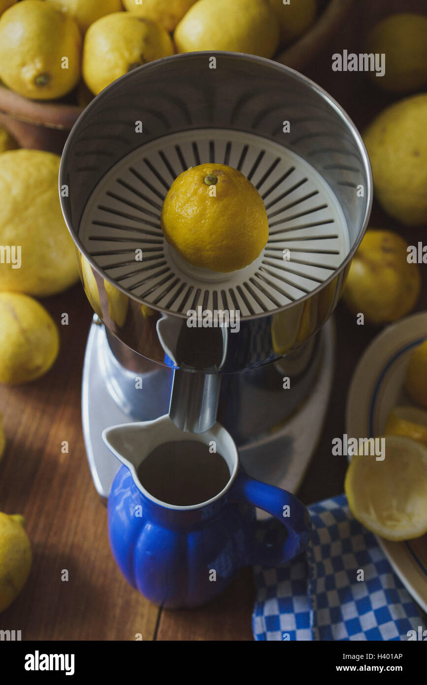 Blauer Krug und elektrische Saftpresse von Zitronen auf Holztisch Stockfoto