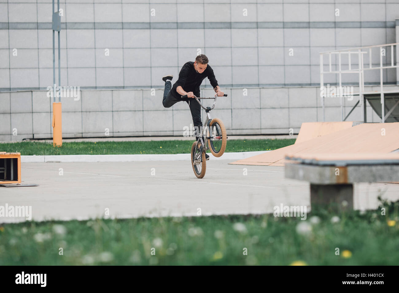 Teenager, die Durchführung von Wheelie mit Fahrrad auf Skateboard-park Stockfoto