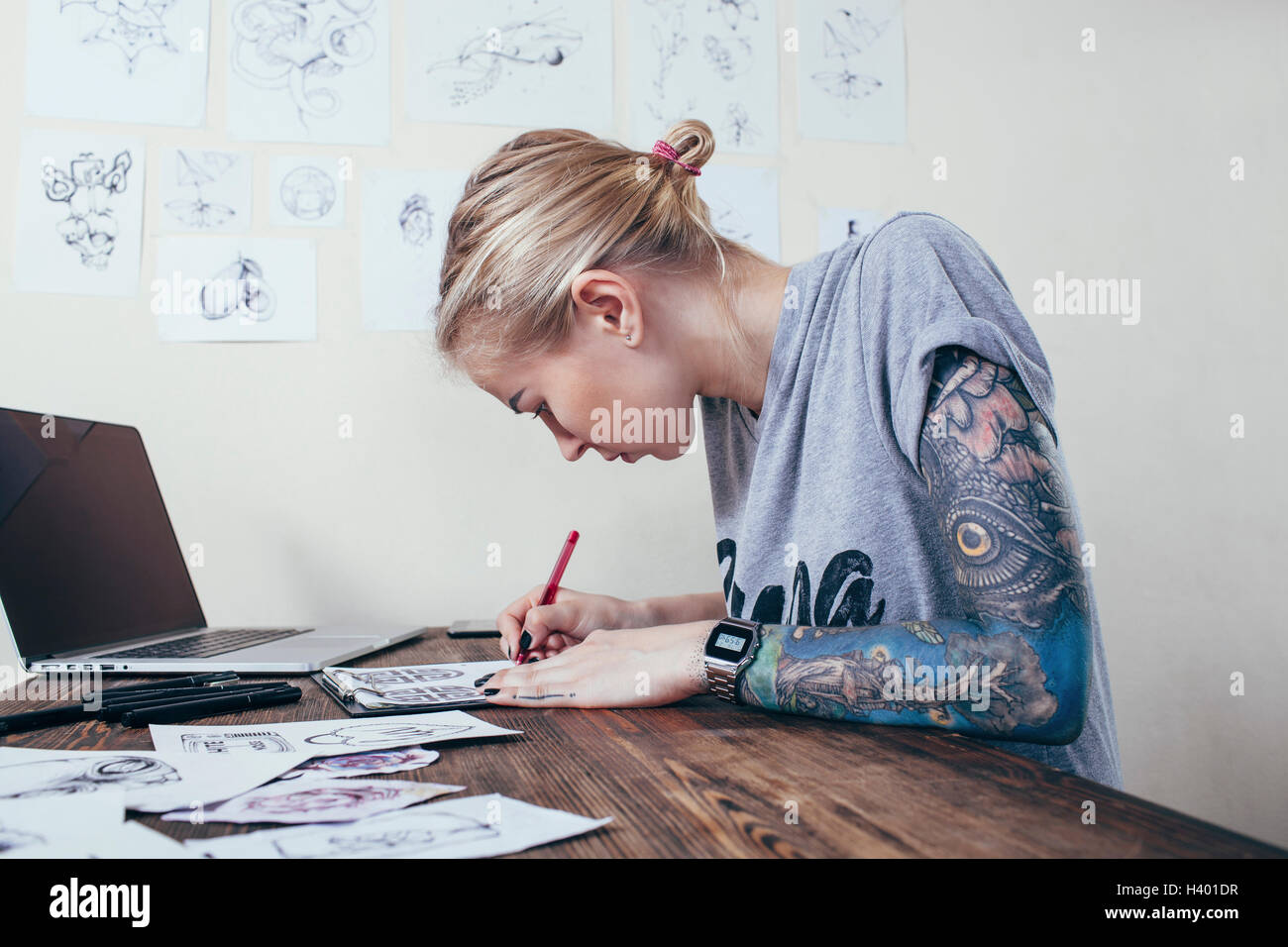 Zuversichtlich Tätowierer arbeiten auf Entwürfe von Laptop im Art studio Stockfoto