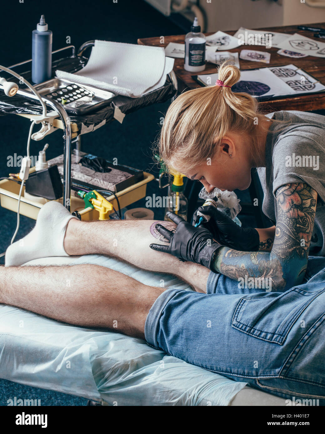 Künstler tätowieren Design am Bein des Mannes im studio Stockfoto