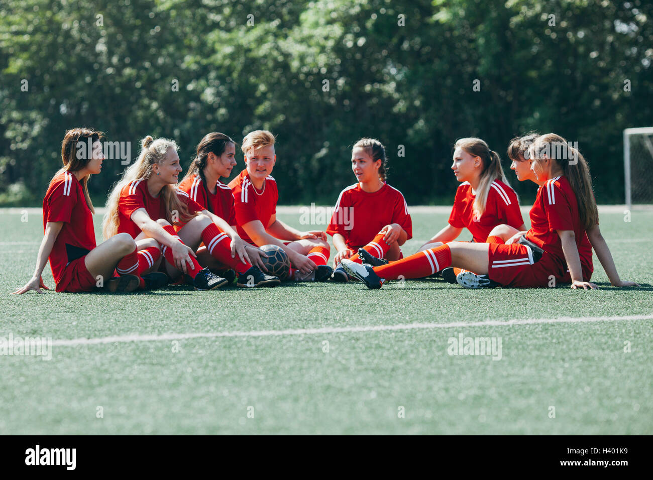 Weibliche Fußballmannschaft sitzen auf Spielfeld Stockfoto