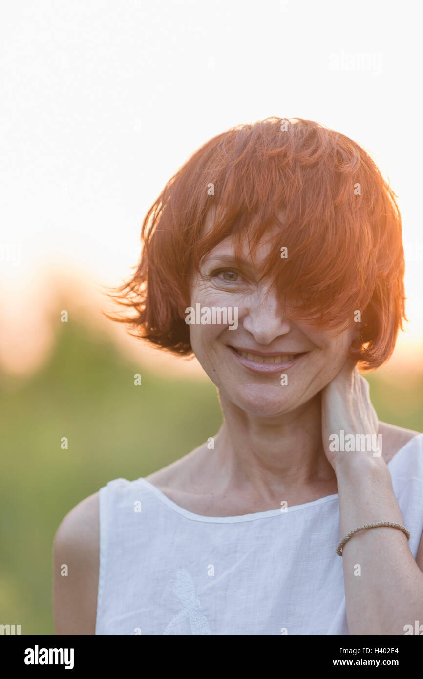 Porträt der lächelnde Frau mit kurzen braunen Haaren stehen im freien Stockfoto