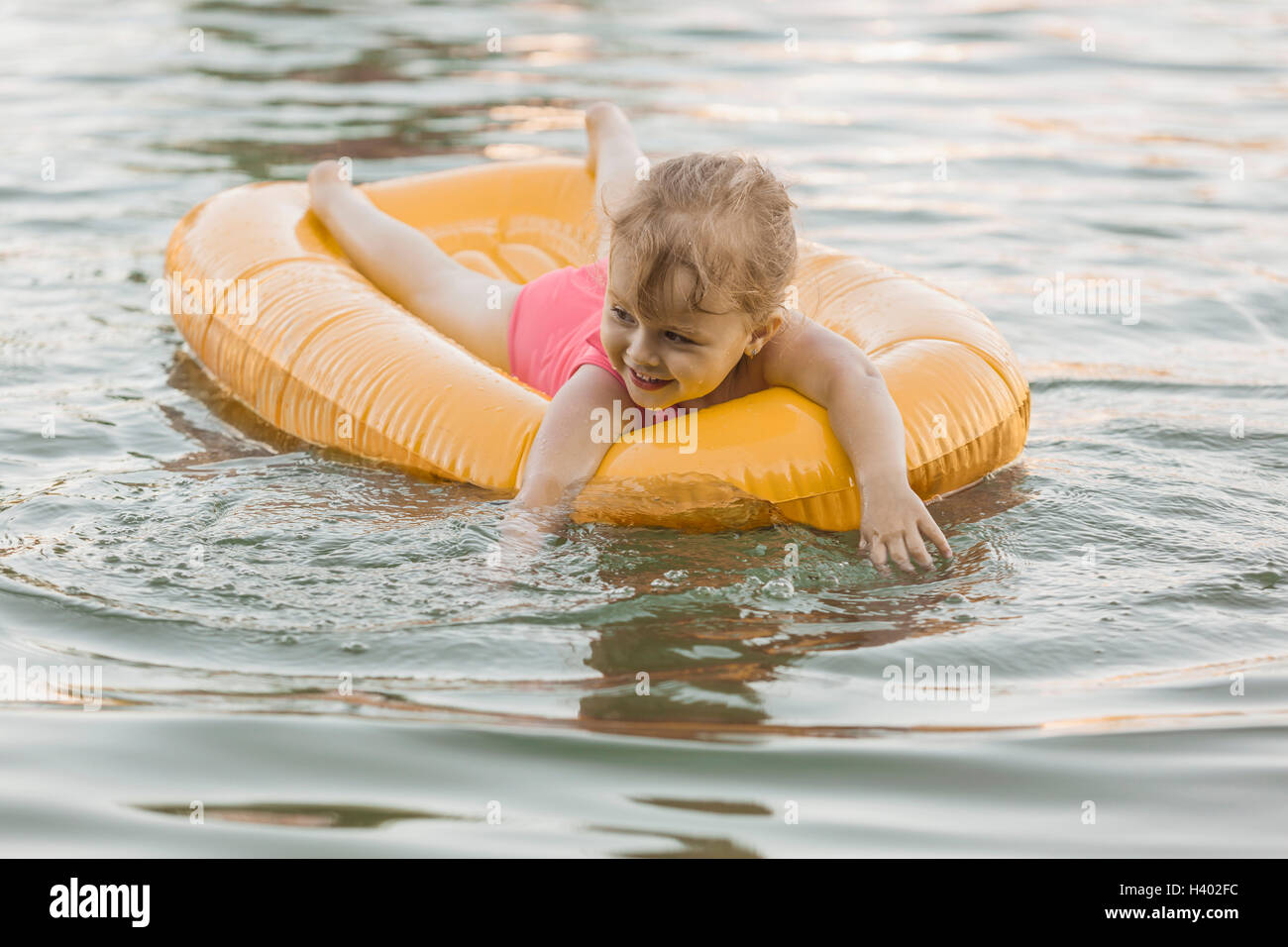 Glückliches Mädchen schwimmenden Floß in See Stockfoto