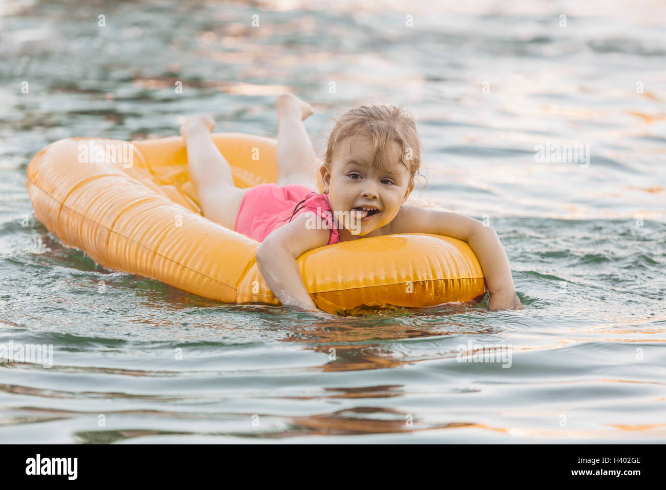 Fröhliches niedliche Mädchen schwimmenden Floß in See Stockfoto