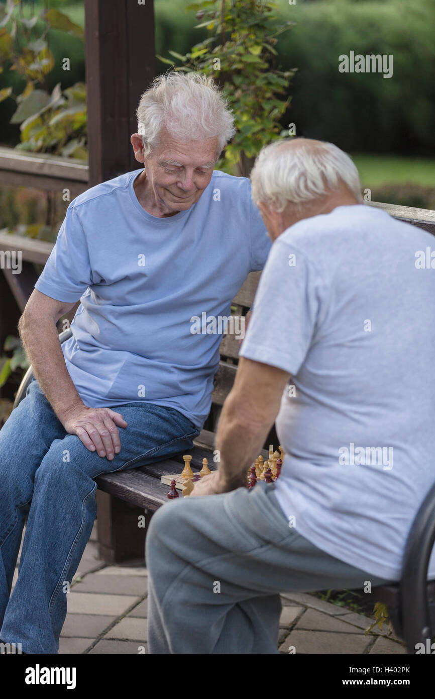 Senioren Freunde spielt Schach auf Parkbank Stockfoto