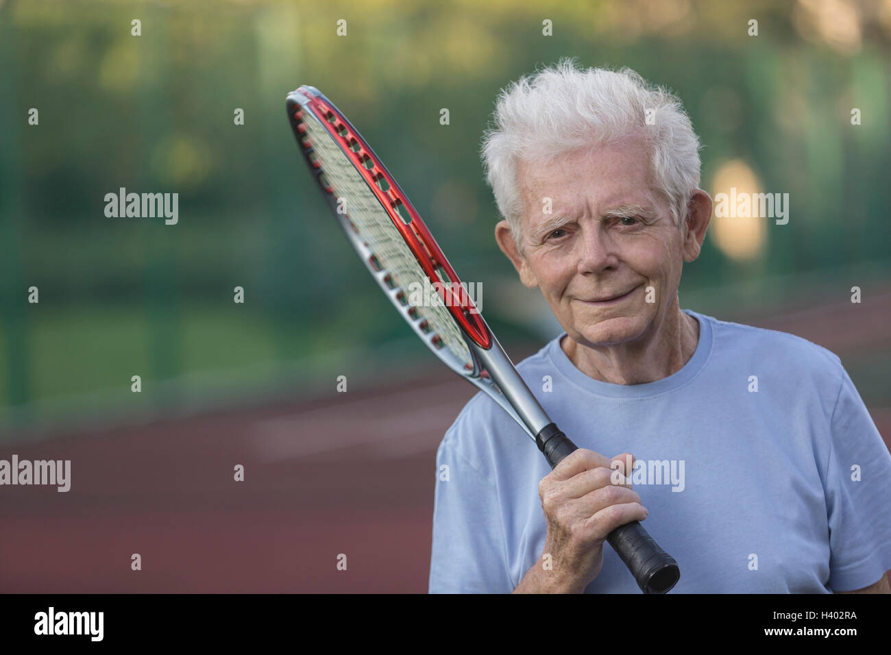 Porträt von lächelnden senior woman holding Tennisschläger am Hof Stockfoto
