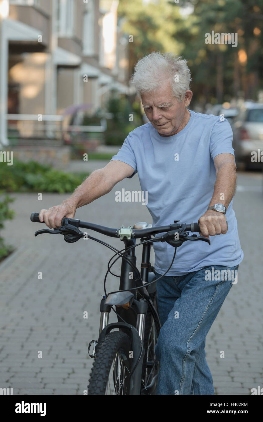 Senior woman Radfahren auf gepflasterten Straße in Stadt Stockfoto